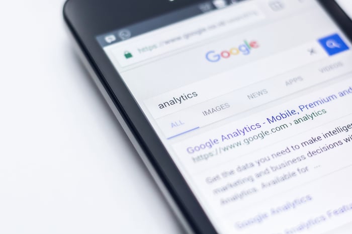 Closeup photo of a smart phone displaying the Google search results for 'analytics'